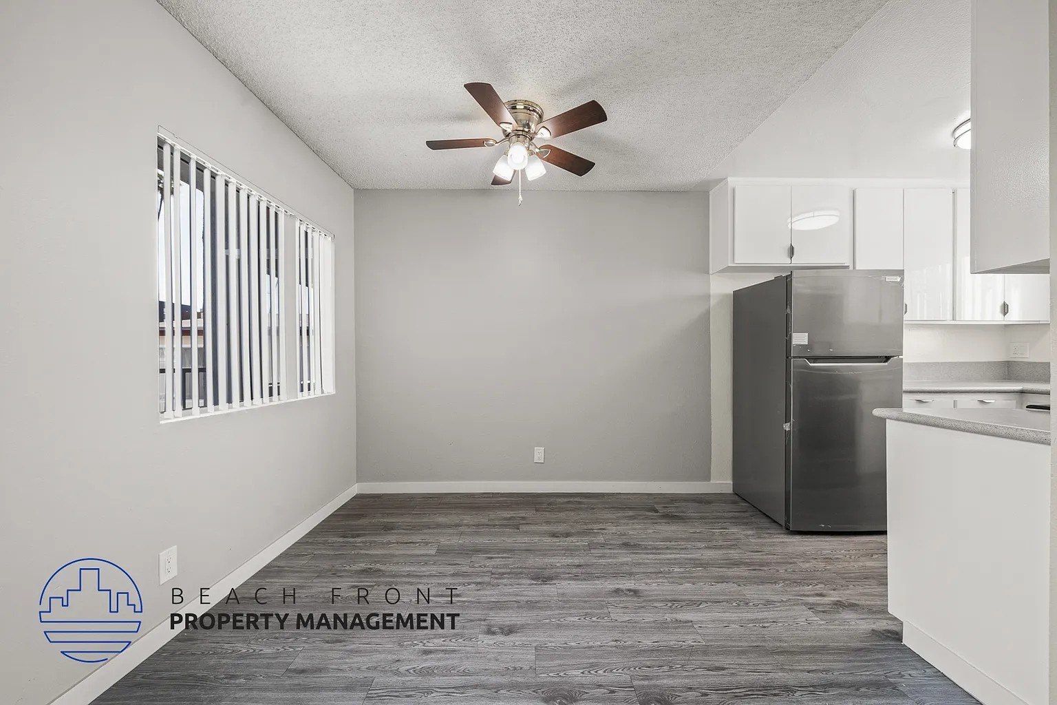 A spacious kitchen and living room with a ceiling fan and wooden flooring.